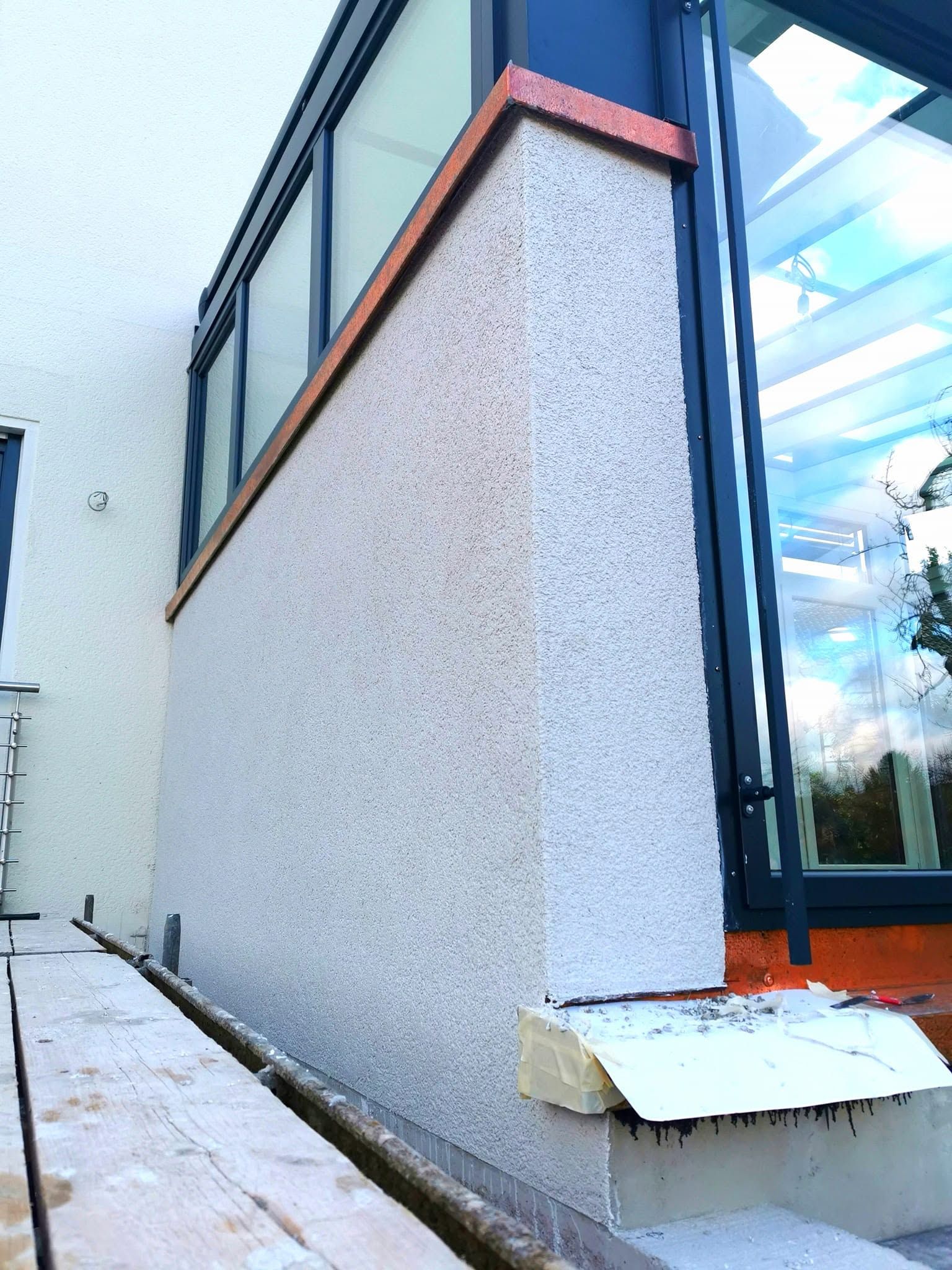 Strukturierter Außenputz an einem Anbau mit verglastem Wintergarten