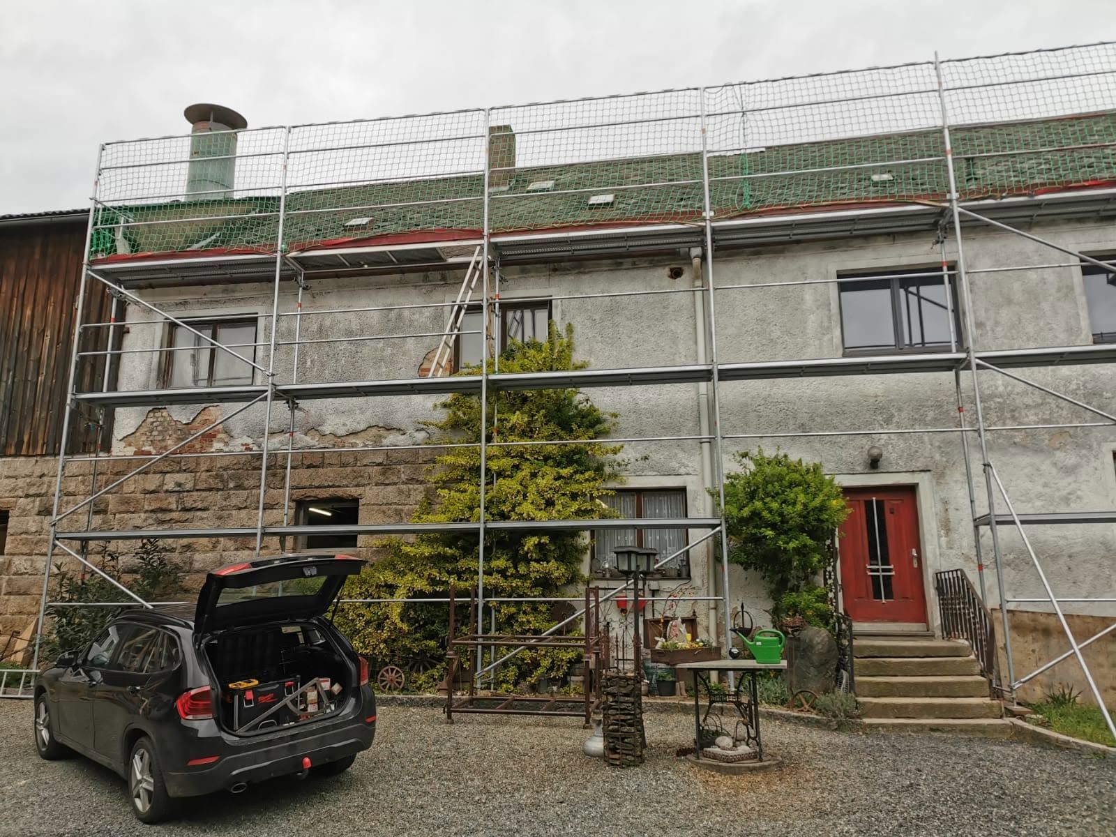 Dasselbe Wohnhaus vor den Arbeiten: eingerüstete, verwitterte graue Fassade