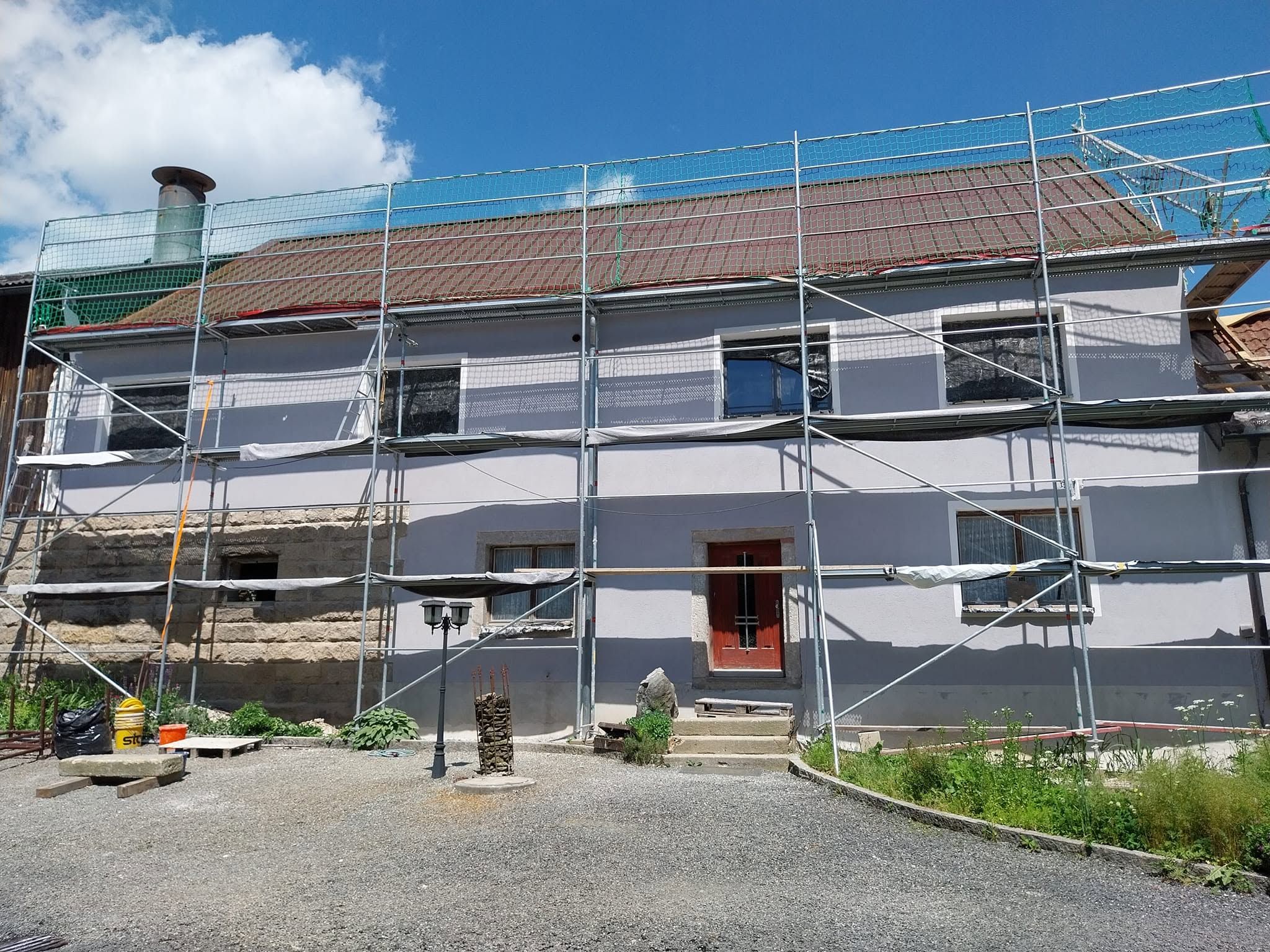 Wohnhaus mit neu verputzter, zweifarbiger Fassade und Gerüst vor blauem Himmel