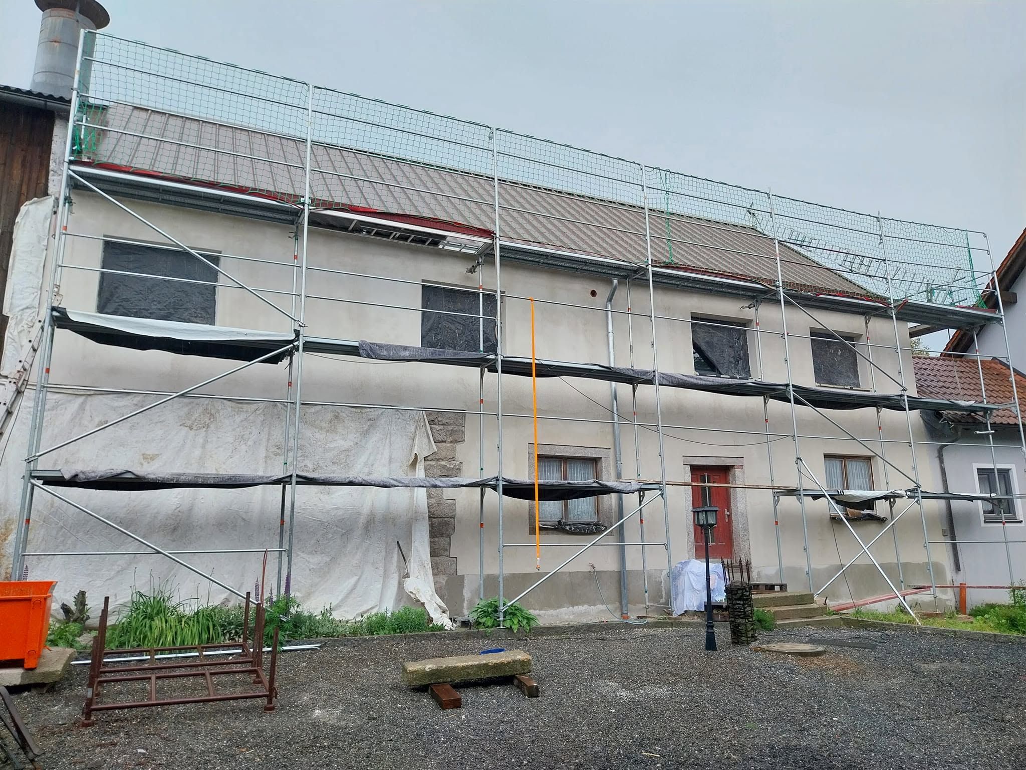 Dasselbe Wohnhaus während der Arbeiten: eingerüstete Fassade mit neuer Putzfläche