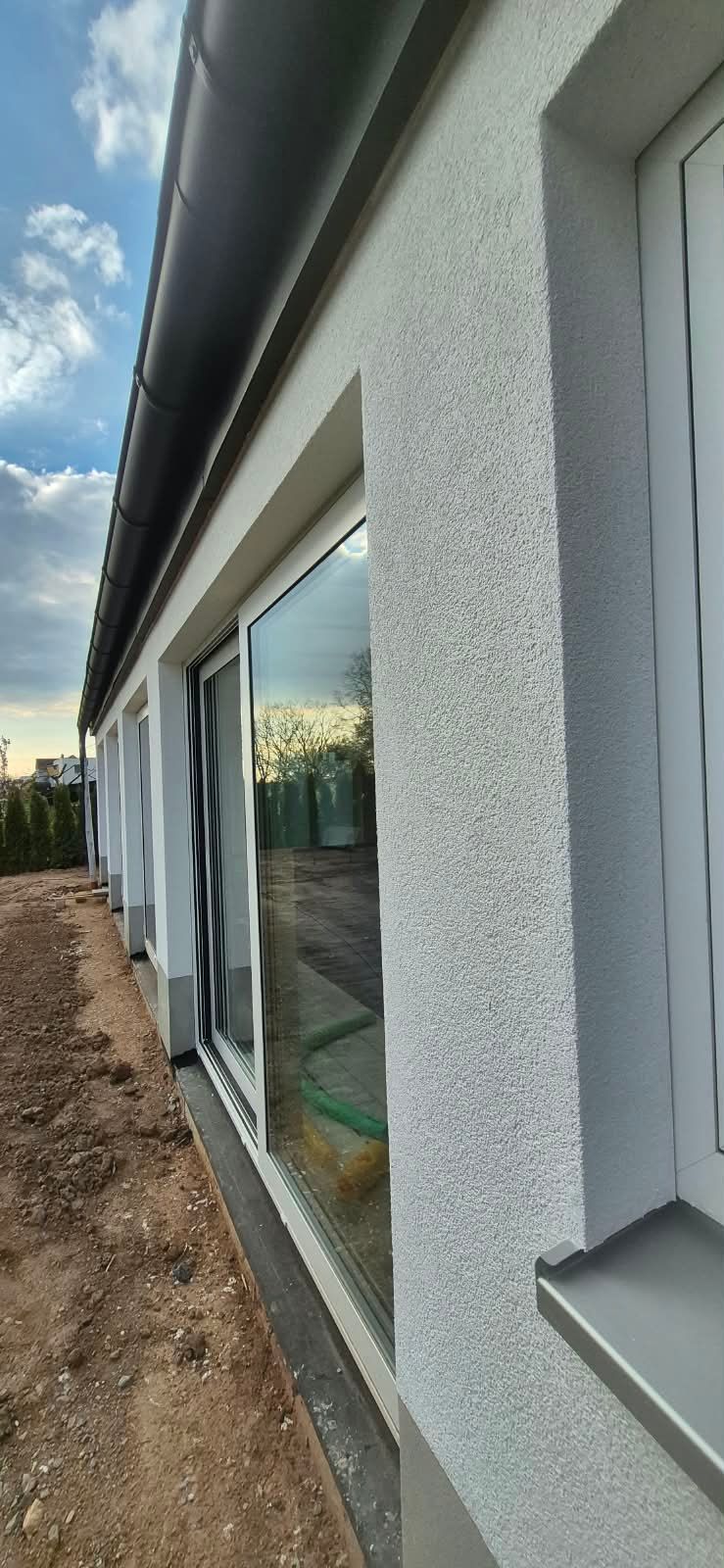 Gedämmte Fassade mit strukturiertem Oberputz und tiefen Fensterlaibungen