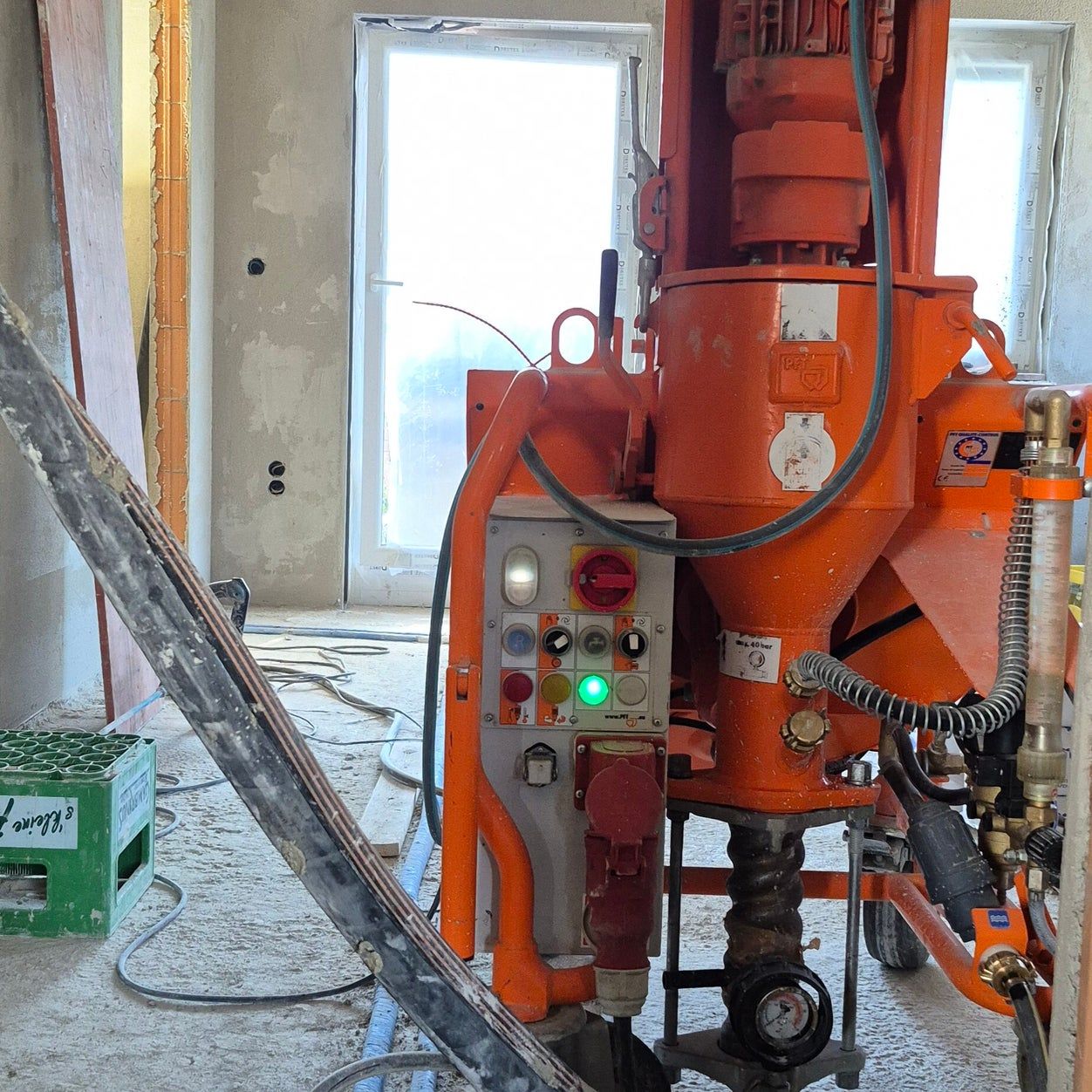 Orangefarbene PFT-Putzmaschine im Einsatz auf einer Innenbaustelle